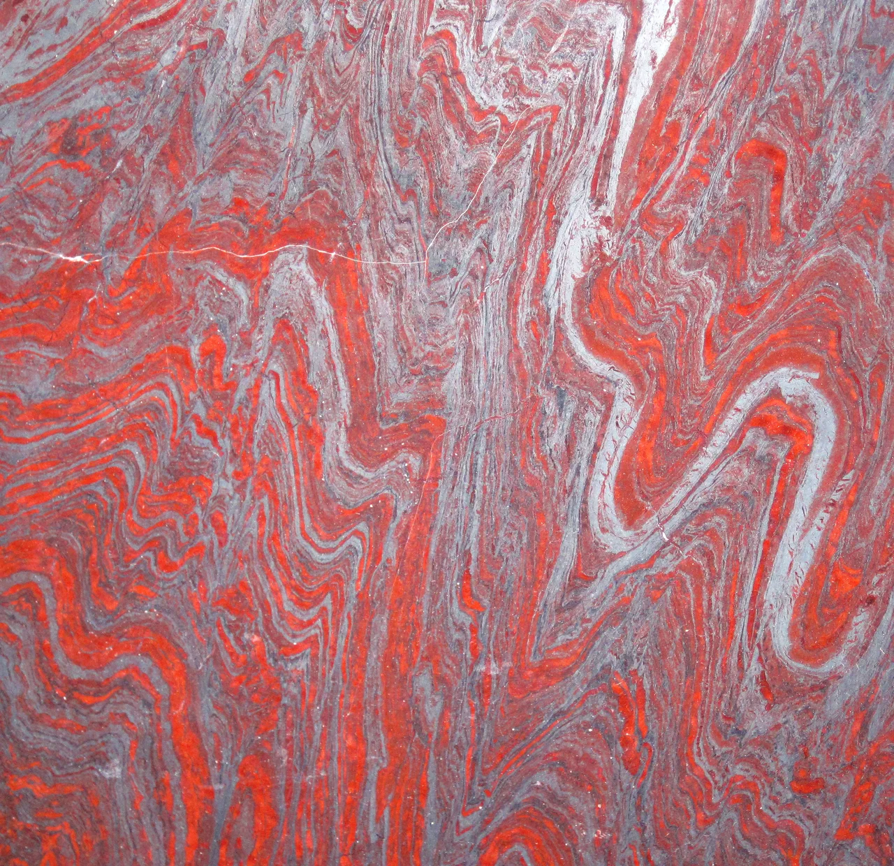 Hollywood Granite - jaspilite meta-BIF (locally called itabirite) from the Paleoproterozoic-aged Minas Supergroup in the Iron Quadrangle District in Minas Gerais State, Brazil.  BIFs in the Iron Quadrangle have long been mined as a source of iron ore.  Recently, BIFs there have been quarried as a source of attractive, high-priced, and very-heavy-for-their-size decorative stones.


Banded iron formations, or BIFs, are extinct, marine sedimentary rocks (most have been well metamorphosed) that usually consist of alternating reddish- and silvery-gray iron-rich layers.  They are most common in the Paleoproterozoic rock record (2.5 to 1.6 Ga).  They represent a time when Earth’s oceans “rusted out” as small amounts of atmospheric free oxygen (O2 gas) combined with dissolved iron in seawater to precipitate as iron oxide minerals.  Some workers hypothesize that bacterial mats on the seafloor mediated the precipitation of iron oxides.

Many specific varities of BIFs exist, including jaspilite, taconite, quartzite-specularites, magnetitites, etc.