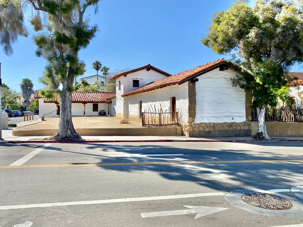Originally built in 1782, this complex of buildings were constructed by the Spanish Colonial Authorities of California to serve as a presidio to protect the nearby Mission Santa Barbara and serve as a center of political influence in the surrounding region.  The adobe buildings stood into the mid-19th Century, when they were slowly demolished and replaced by a neighborhood with roads platted through the middle of the presidio in the 1850s.  By the mid-20th Century, only a single structure, the El Cuartel, which is the second-oldest existing building in California, remained standing, having been transformed into a private residence.  The buildings were largely reconstructed after an archaeological investigation, with the first part of the complex being rebuilt between 1983 and 1985.  The buildings consist of one-story adobe structures with red terra cotta tile roofs, exposed rafter tails, porches with wooden columns, and small window openings surrounding a central dirt courtyard, which has been partially restored, and a larger and taller chapel at the center of the western end of the courtyard, with a gabled roof, an arched entrance bay, and small tower with two bells.  The buildings are divided by modern streets laid out after the Presidio had been largely demolished, with the ends of the reconstructed buildings revealing the interior structure of the presidio buildings where they are cut away along the streets.  The original buildings in the complex were listed on the National Register of Historic Places in 1973.  Today, the reconstructed Presidio serves as a historical museum operated by the Santa Barbara Trust for Historic Preservation.