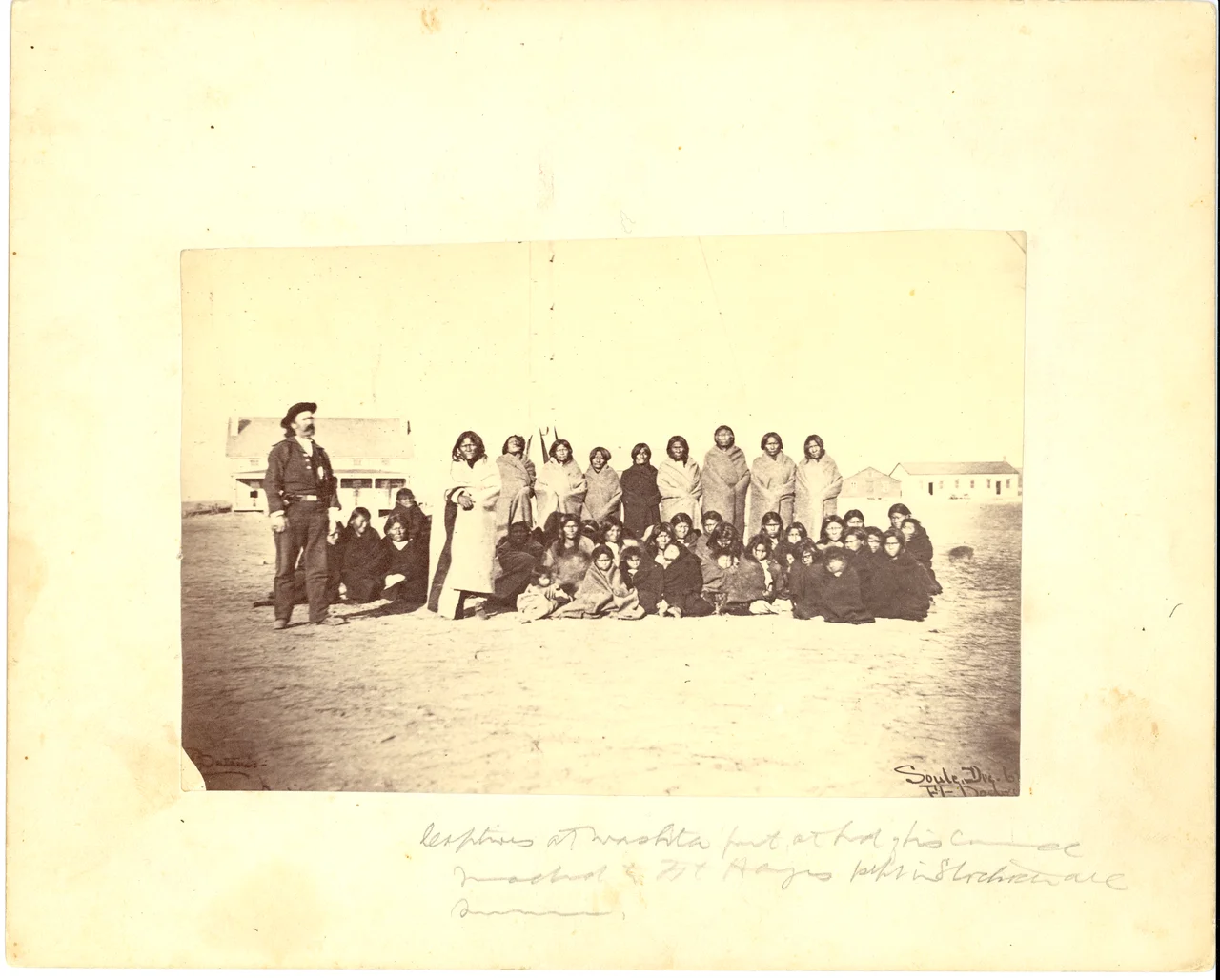 LIBI_00019_00392; This item is an original albumen photograph of a group of Cheyenne (Southern) women and children captured at the Battle of the Washita, being held at either Fort Hayes or Fort Dodge.  The photograph is 4 1/2 x 6 7/8" (8 x 9 7/8" mounted) and was produced circa 1869 by W.S. Soule.  The image is believed to have been taken at Camp (Fort) Supply, Indian Territory.  On the front, a mostly illegible handwritten caption provides a description of the captives at the Washita fort.  "Soule [illegible word]" is written on the image in the lower right corner.  On the verso, a handwritten notation in pencil reads, "Prisoners captured in the Battle of the Washita--Scout with them."Note: "Pkg 6/Box 3" handwritten on the verso.   Photograph reprinted in "The Custer Album" by Lawrence A. Frost, page 95.; Print, Photographic [Mounted on Card]; Courtesy of the National Park Service, Little Bighorn Battlefield National Monument, LIBI_00019_00392, William
Keywords: little bighorn battlefield national monument