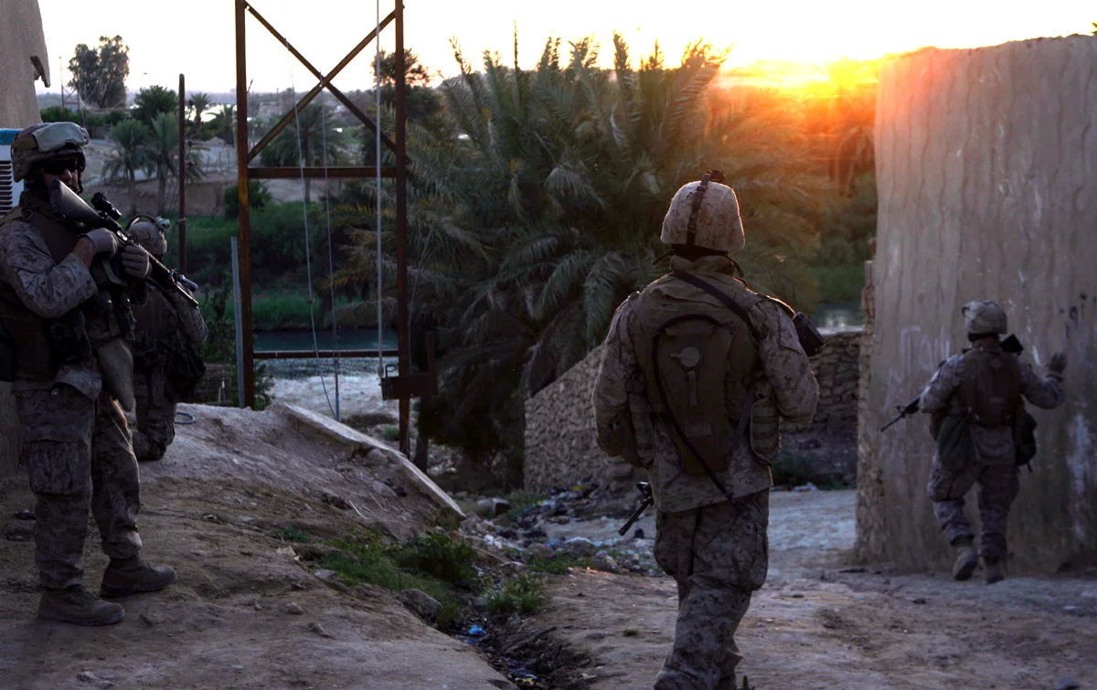 Original Caption: As the sun begins to set in western Al Anbar Province, Iraq, U.S. Marines from the Hawaii-based Kilo Company, 3rd Battalion, 3rd Marine Regiment patrol through back alleys in Haqlaniyah, Iraq, June, 1, 2006. The Marines were searching for insurgents and contraband in the city of 30,000, which is nestled along the Euphrates River northwest of Baghdad. Marines and Iraqi soldiers frequently patrol Haqlaniyah, where arguably some of the fiercest violence by insurgents against Coalition Forces occurs. Since their arrival more than two months ago, the Marines have engaged insurgents frequently. Most recently, the Marines fought insurgents hiding in an abandoned hotel, which was later bombed by U.S. military aircraft.