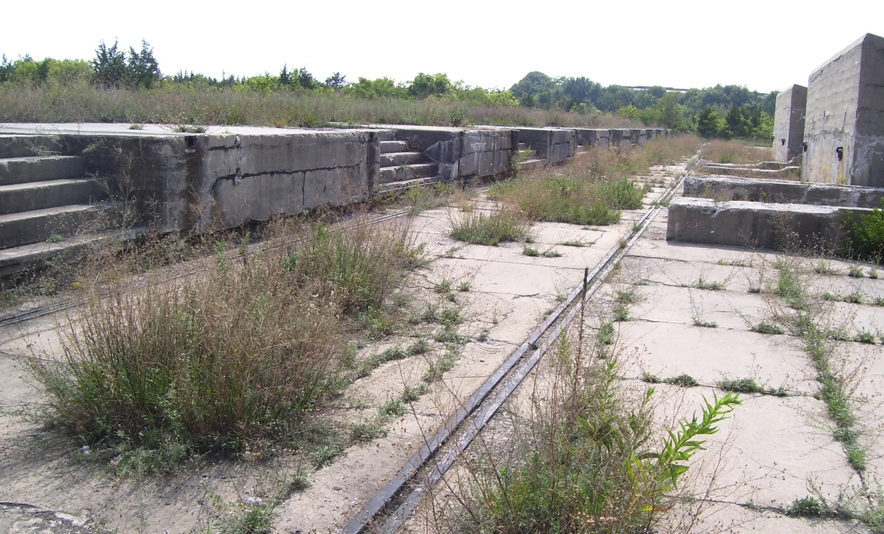 Abandoned concrete gun platforms, formerly part of the Proof Battery of the Sandy Hook Proving Ground, in use from 1901-1919. To the right are protective walls, or "traverses". Soldiers used a 20-foot gantry crane on rails to lift guns and carriages onto the platforms to be tested, or "proved". Sandy Hook is now part of the Gateway National Recreation Area; these platforms are near North Beach.