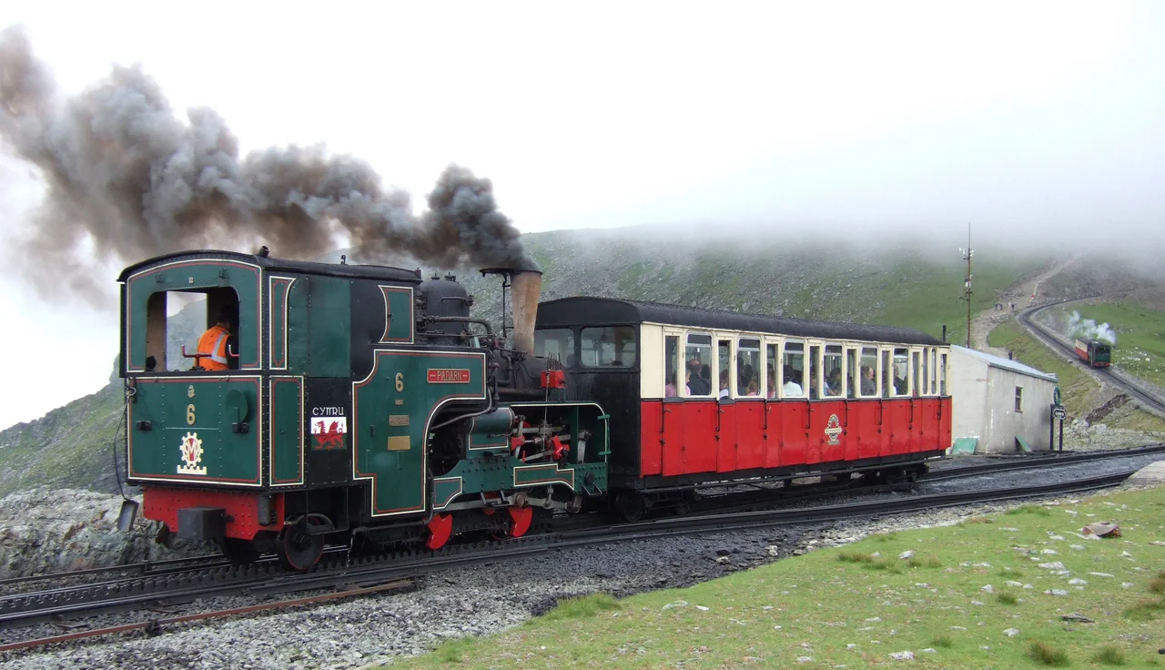 Snowdon Mountain Railway trains pass at Clogwyn. No.6 'Padern' is ascending while No.2 'Enid' is descending out of the clouds. 19th July 2005
Photographer - A.M.Hurrell
Camera - Fuji FinePix F10
Modified - Trimmed and file size reduced using Adobe Photoshop 5.0LE