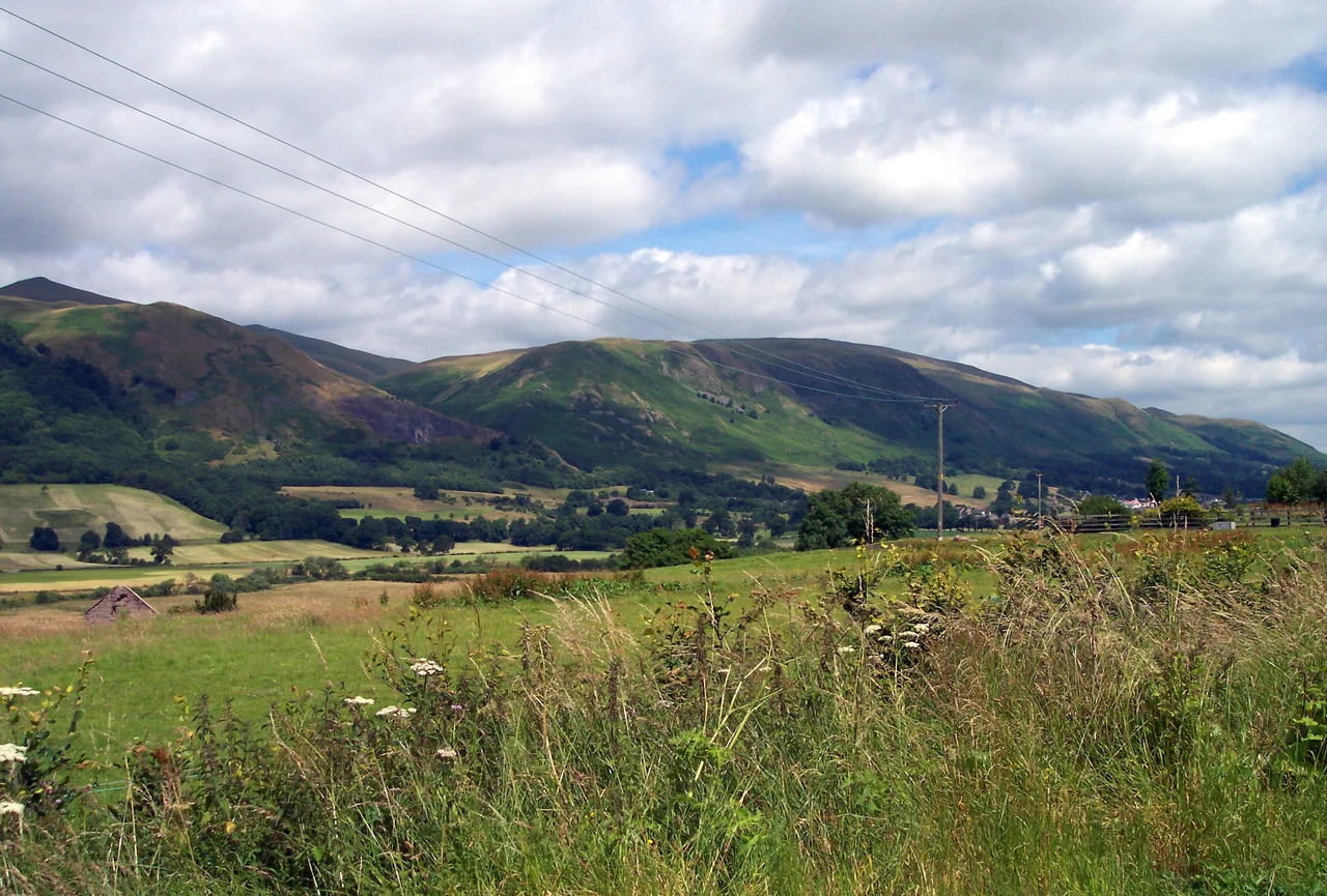 The Ochil Hills as seen from South-West of Tillicoultry. In the foreground, (L-R) Wood Hill (525m) and Elistoun Hill (497m). Behind them on the left of the photo, The Law (638m) can be seen rising above the two. Tillicoultry's Craigfoot Quarry can be seen just below the right slope of Wood Hill.
Photo taken by myself, Hellinterface, July 2005.