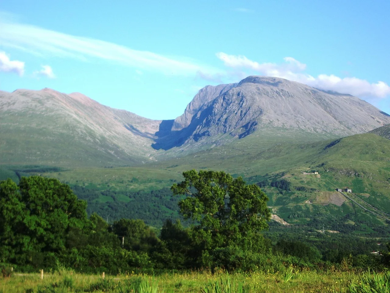 Ben Nevis, 1,344 metres, Scotland. Photograph taken from Banavie about 8 km north west. 18:55, 11 July 2005. The summit is beyond and to the left of the apparent highest point, Càrn Dearg North, 1,221 metres, (many Scottish mountains are called Càrn Dearg). Càrn Mòr Dearg, 1,223 metres, is to the left, connected to the Ben by the Càrn Mòr Dearg Arête at the head of Coire Leis (slightly in shadow). The pipelines of the Lochaber hydroelectric scheme are visible lower right.
