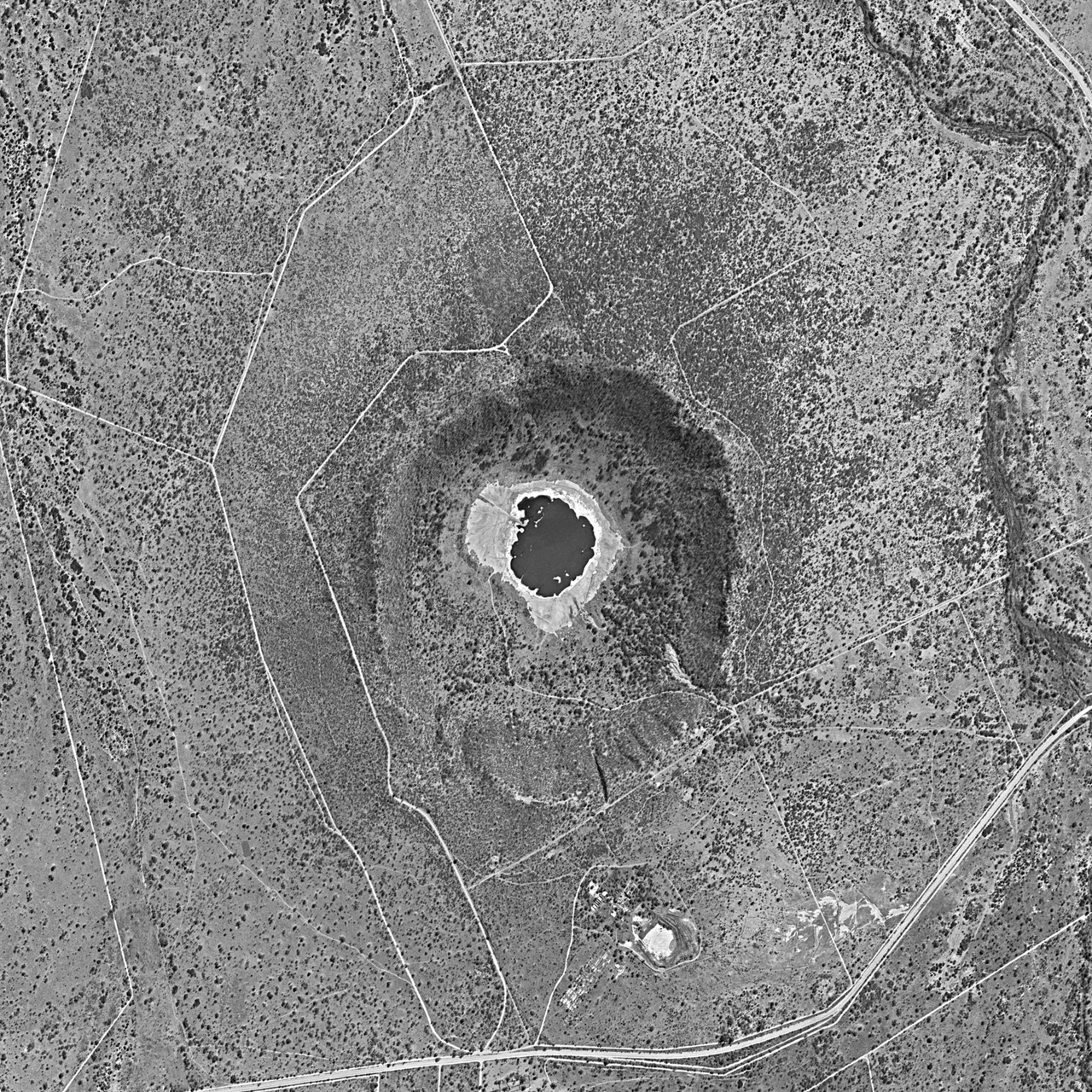 Tswaing crater, within Tswaing Nature Reserve, north of Johannesburg, South Africa, in 1984.  Approximate north at top.  The creek at right is called Soutpanspruit.  D3C1219-200530F026 is the panoramic camera photo number.  This is cropped from a much larger full image.  Image width is about 3.04 km.