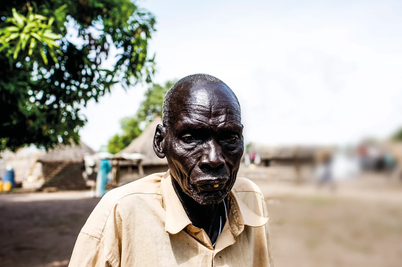 I have lived many years and know how we lived before all the wars. We were cattle keepers and could move freely grazing our bulls. Yes, there were clashes and fights like in every society, but they were small and could be resolved with time and reason. There were traditional systems that worked. We were free to travel and see different lands, meet new people and share our experiences, all the while trading in cattle and making money. This has not been the reality for a long time.  
I was in Bor with my family when the fighting broke out. I told them to run because I am old and disabled. I lost my leg during the first war. I was left alone and on the first day, men walked into my house. They were Nuer. One of them saw me and wanted to kill me but his friend stopped him in his tracks.
He looked at the young man and asked, ‘Look at this man. If you kill him, what will you accomplish? This man has done nothing wrong to you and yet you want to kill him. What will you gain from doing that?’
The young man lowered his gun and left the house. I don’t know the name of the man who saved my life but I am very grateful for what he did. Before he left, he looked at me and said, ‘Stay here and don’t make any noise. I will lock the door behind me. Do not open it for anyone else.’
That man saved my life. I wish I knew his name and where to find him so that I can thank him again.
‘He gives me hope that there is still room for healing despite all wounds we have endured.
There is still hope if our systems transform towards reconciliation and healing.’

Photo: Mackenzie Knowles Coursin/Oxfam