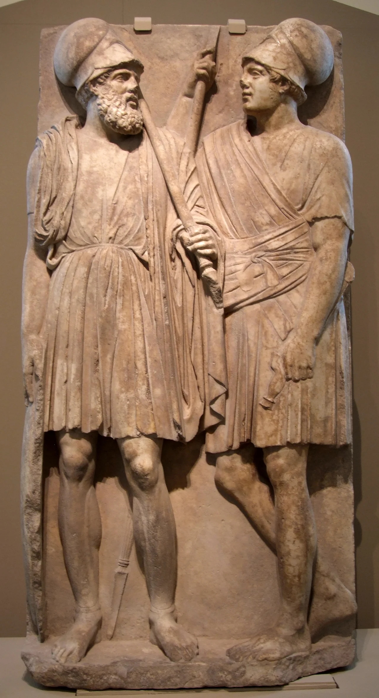 Stele with two warriors of the Bosporan Kingdom. From Taman peninsula (Yubileynoe), Southern Russia, 3rd quarter of the 4th century BC. Marble, Pushkin museum

The marble relief was found in 1985. It is 1.88 m high, above 0.85 m and below 0.94 m wide. The plate is 0.25 m thick, the relief protruding 0.12 m. Also the whole surface of the plate is worked – the shield of the older warrior is reaching to the very margin of the stone. Two soldiers are represented, gazing each other. The bearded soldier has all attributes of a hoplite; the younger is only holding a spear.