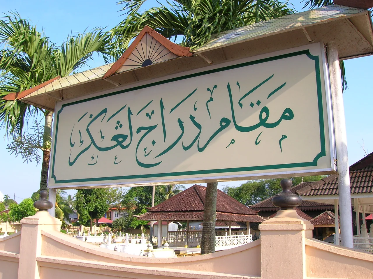 Signboard of the Makam Diraja Langgar located in the state of Kelantan in Malaysia. The signboard uses the Jawi script written in simple Islamic calligraphy. The Jawi text reads: مقام دراج لڠڬر
The Jawi script does not use diacritics. Diacritics are used when writing Jawi in Islamic calligraphy style.